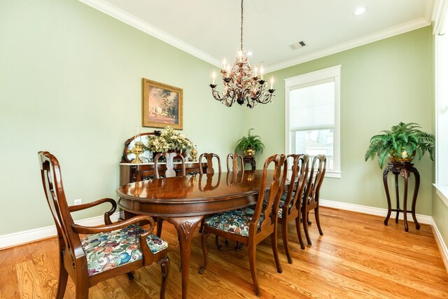 dining room with light wood-type flooring, crown molding, and a notable chandelier