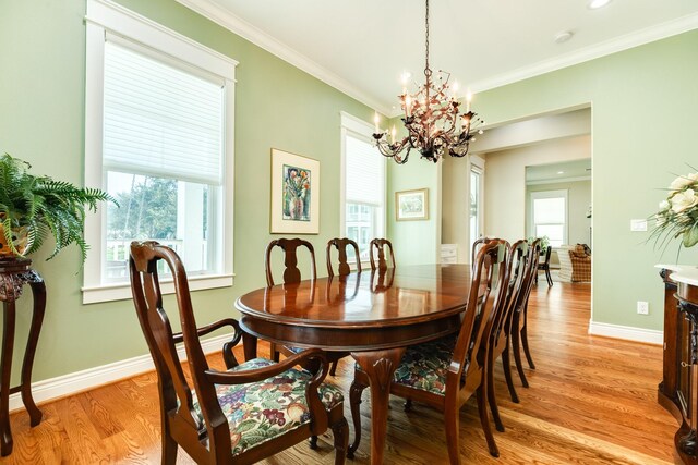 dining area featuring a notable chandelier, light wood-type flooring, a healthy amount of sunlight, and crown molding