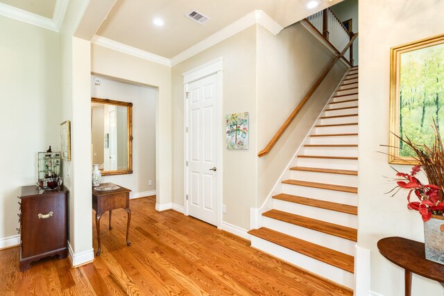 entrance foyer featuring ornamental molding and light hardwood / wood-style flooring