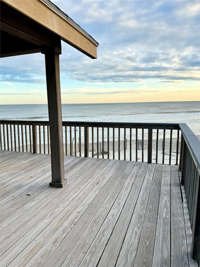 deck at dusk with a beach view and a water view