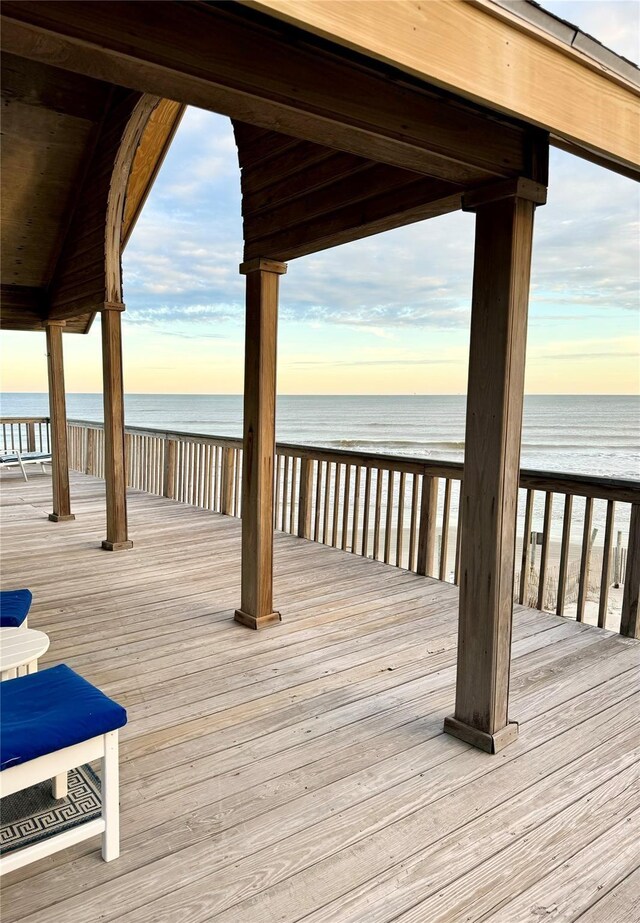 deck at dusk with a water view and a beach view