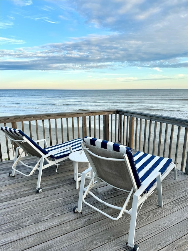 wooden deck featuring a water view and a beach view