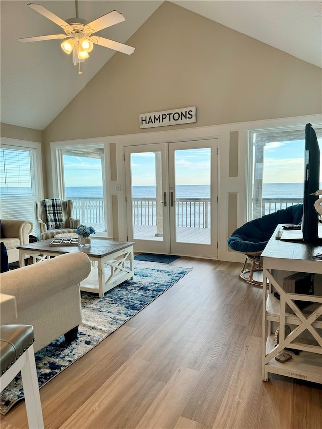 living room with a wealth of natural light, hardwood / wood-style floors, ceiling fan, and high vaulted ceiling