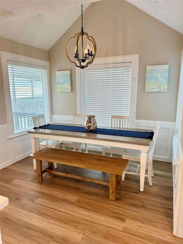 dining space with a notable chandelier, lofted ceiling, and hardwood / wood-style floors