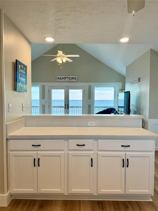 bathroom featuring vaulted ceiling, vanity, a textured ceiling, wood-type flooring, and ceiling fan