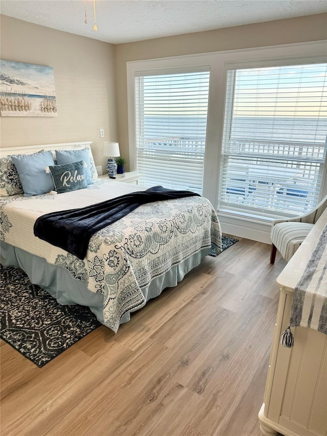 bedroom featuring multiple windows, a textured ceiling, and hardwood / wood-style flooring