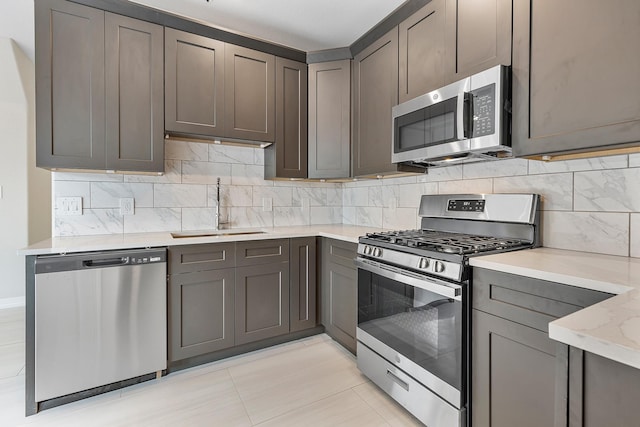 kitchen featuring tasteful backsplash, appliances with stainless steel finishes, sink, and light stone counters