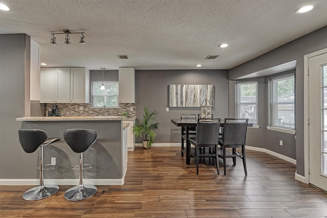 kitchen with a textured ceiling, plenty of natural light, and white cabinetry