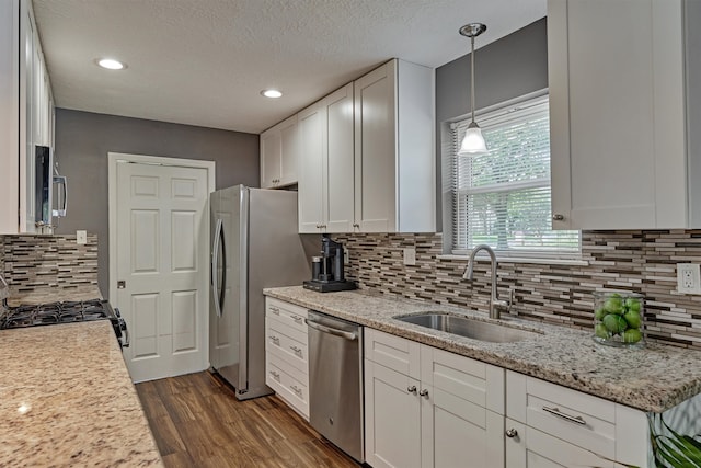 kitchen featuring white cabinets, sink, decorative light fixtures, appliances with stainless steel finishes, and dark hardwood / wood-style flooring