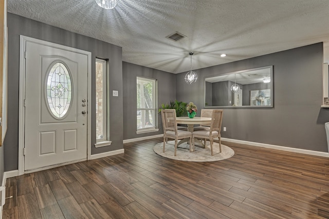 entrance foyer with an inviting chandelier, a textured ceiling, and dark hardwood / wood-style floors