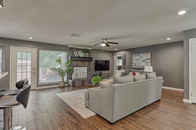 living room featuring a textured ceiling, ceiling fan, and hardwood / wood-style flooring