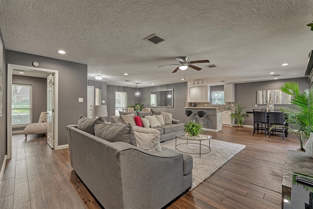 living room featuring a textured ceiling, ceiling fan, and dark hardwood / wood-style flooring