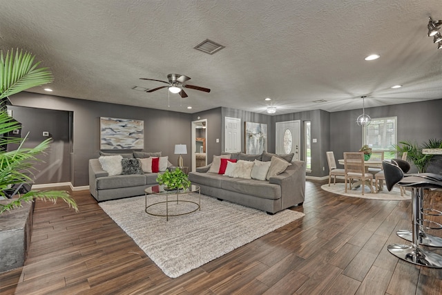 living room featuring a textured ceiling, ceiling fan, and dark hardwood / wood-style flooring