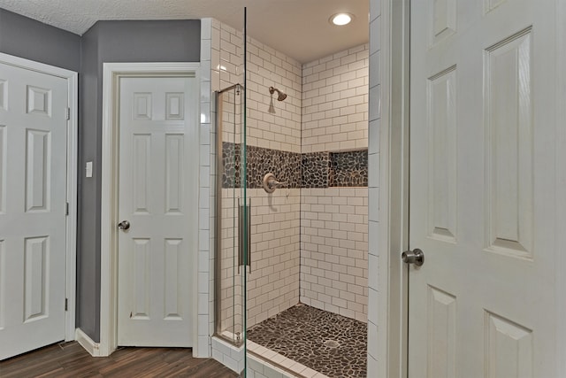 bathroom featuring a textured ceiling, hardwood / wood-style floors, and a shower with shower door