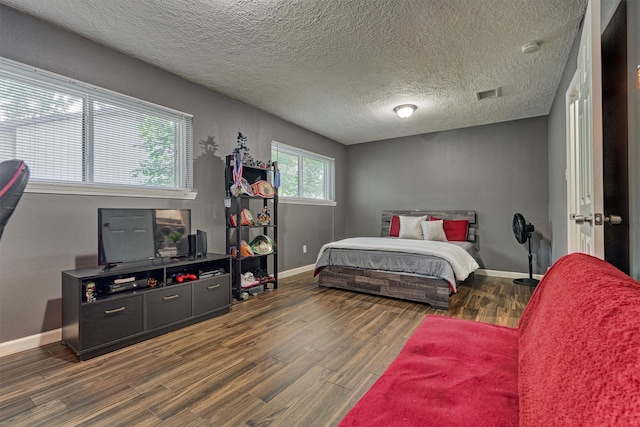 bedroom with a textured ceiling and dark hardwood / wood-style flooring