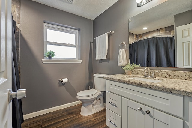 bathroom featuring vanity, a textured ceiling, wood-type flooring, walk in shower, and toilet