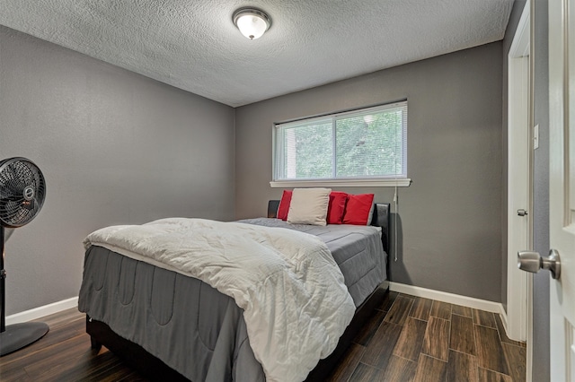 bedroom with a textured ceiling and dark wood-type flooring