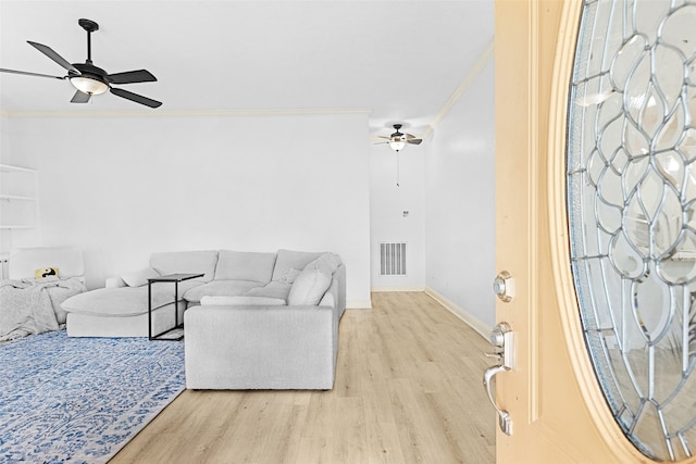 living room with light wood-type flooring, ceiling fan, and crown molding