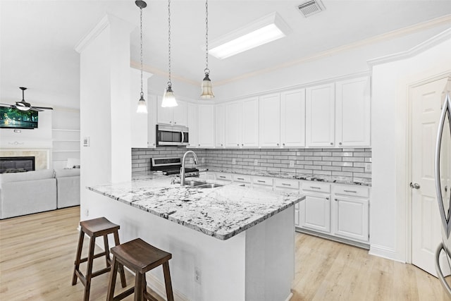 kitchen with sink, kitchen peninsula, ceiling fan, white cabinetry, and a breakfast bar area