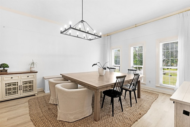 dining area featuring light wood-type flooring, crown molding, and a notable chandelier