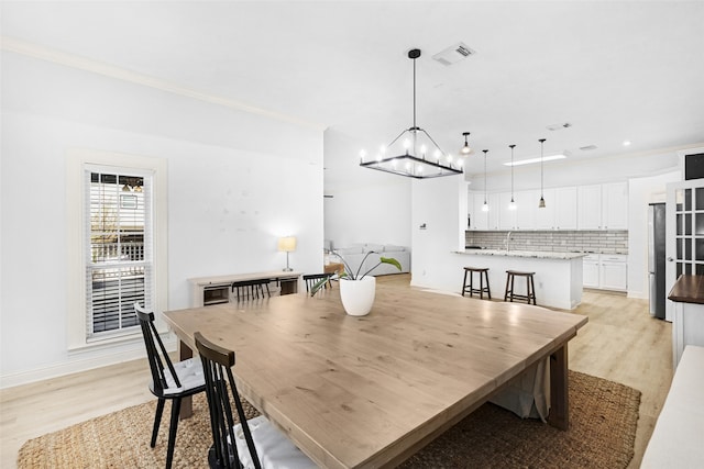 dining area with light hardwood / wood-style flooring, ornamental molding, and sink