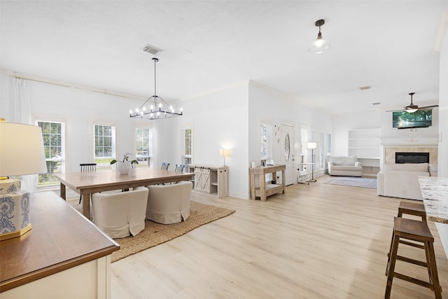 dining area with ceiling fan with notable chandelier, light hardwood / wood-style floors, and ornamental molding