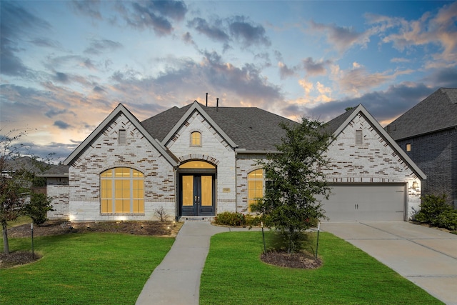 french country home featuring french doors, a garage, and a lawn