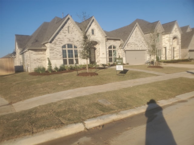 french country home featuring a front lawn and a garage