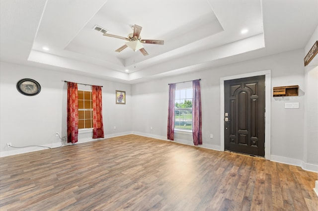 foyer entrance with wood-type flooring, a raised ceiling, and ceiling fan