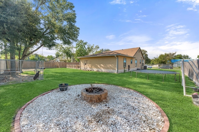 view of yard featuring a trampoline and a fire pit