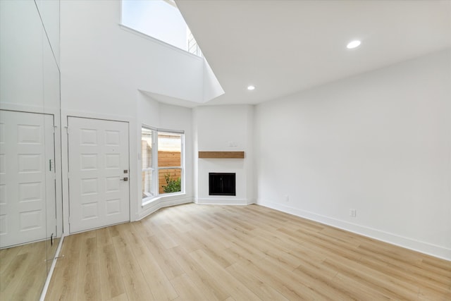 unfurnished living room featuring light hardwood / wood-style floors and a high ceiling