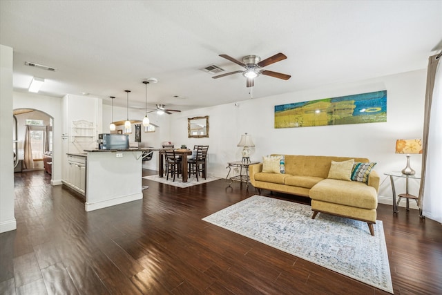 living room featuring dark wood-type flooring and ceiling fan