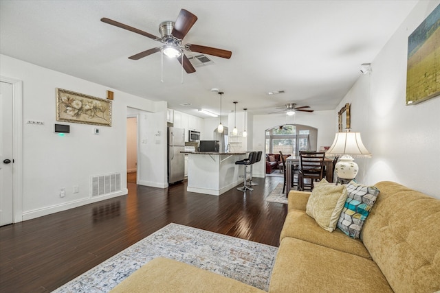 living room featuring ceiling fan and dark hardwood / wood-style flooring