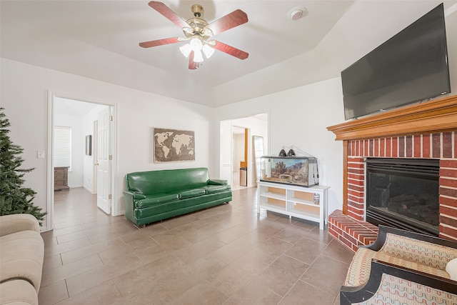 living room with ceiling fan, tile patterned floors, and a brick fireplace