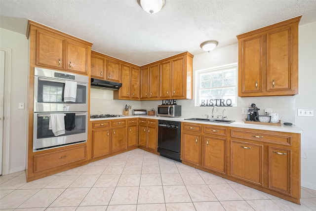 kitchen with light tile patterned flooring, appliances with stainless steel finishes, sink, and a textured ceiling