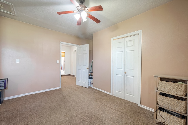 unfurnished bedroom featuring ceiling fan, light colored carpet, a textured ceiling, and a closet