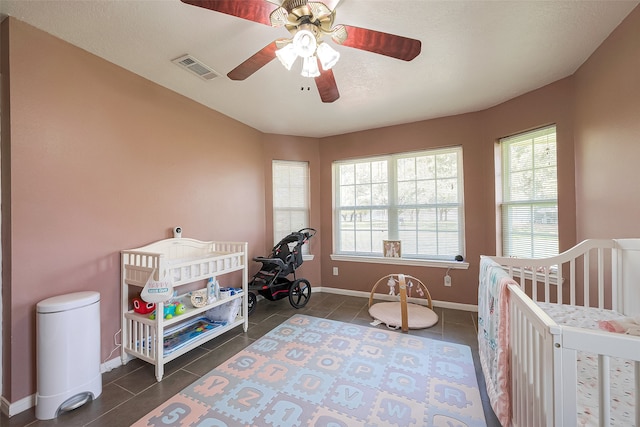 tiled bedroom with ceiling fan and a nursery area