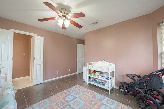 interior space with dark tile patterned floors and ceiling fan