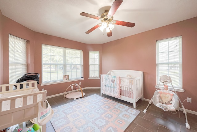 tiled bedroom featuring ceiling fan, a crib, and multiple windows