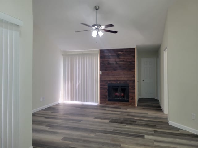 unfurnished living room featuring a large fireplace, ceiling fan, and dark wood-type flooring