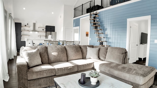 living room featuring wooden walls, a towering ceiling, and dark hardwood / wood-style flooring