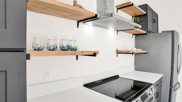 kitchen with stainless steel refrigerator, black stove, range hood, and gray cabinets