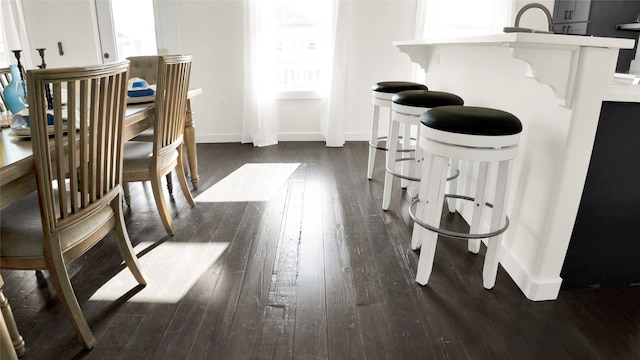 interior space featuring a kitchen bar, white cabinetry, and dark wood-type flooring