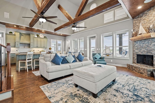 living room featuring hardwood / wood-style flooring, beam ceiling, a fireplace, high vaulted ceiling, and ceiling fan