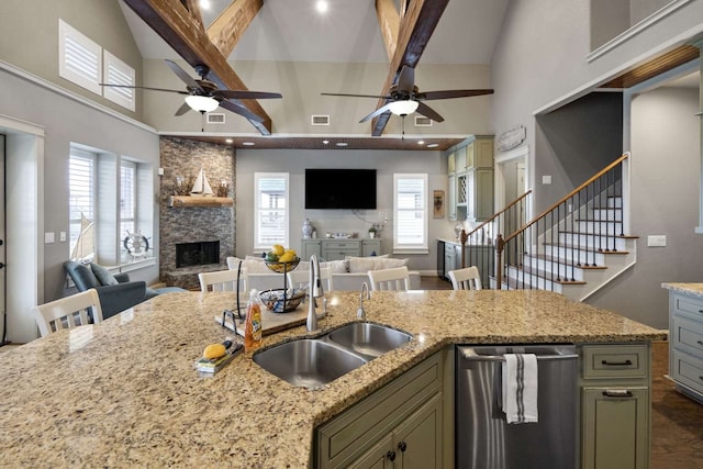 kitchen featuring dishwasher, beam ceiling, a stone fireplace, light stone countertops, and ceiling fan