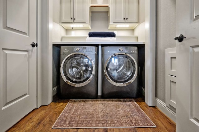 clothes washing area with cabinets, dark hardwood / wood-style flooring, and washing machine and clothes dryer