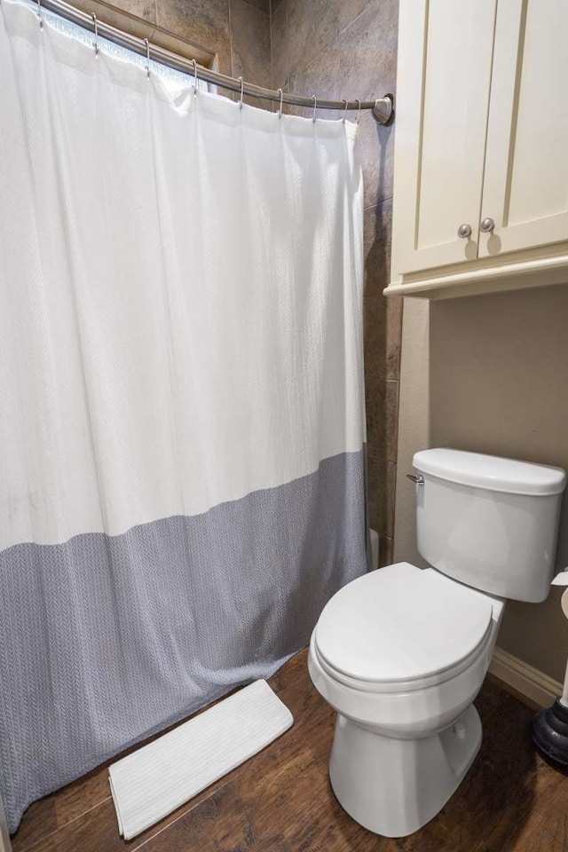 bathroom with hardwood / wood-style flooring, toilet, and curtained shower