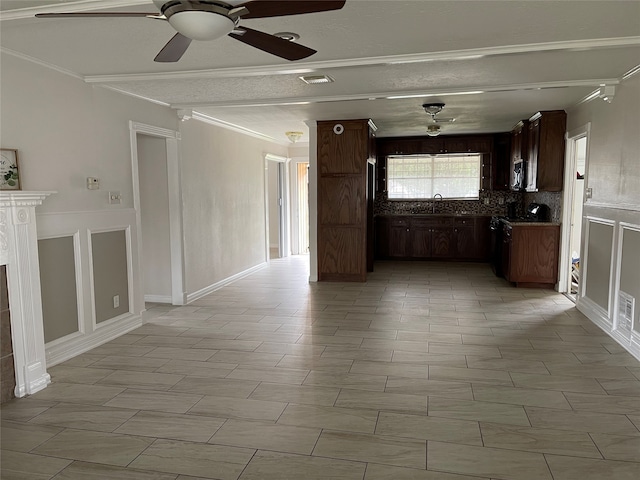 unfurnished living room featuring ornamental molding, ceiling fan, a tile fireplace, and a textured ceiling