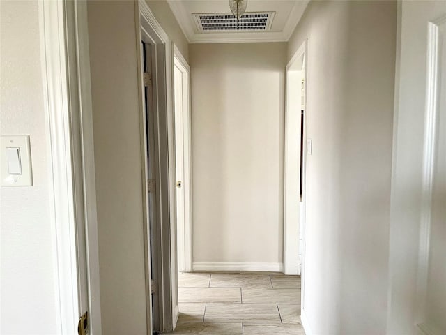corridor with crown molding, baseboards, and visible vents
