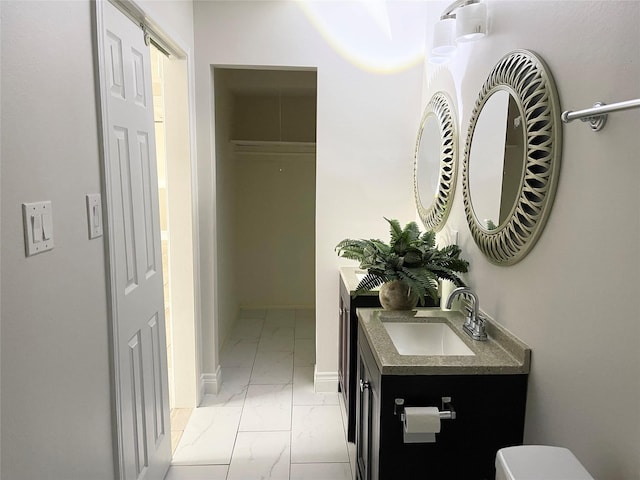 bathroom featuring vanity, marble finish floor, baseboards, and toilet